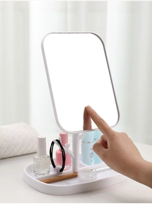 Close-up of a white desktop makeup mirror with a storage base for small cosmetics