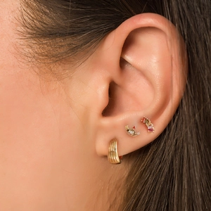 Close-up of gold hoop and colorful gemstone crescent cartilage studs on a female ear