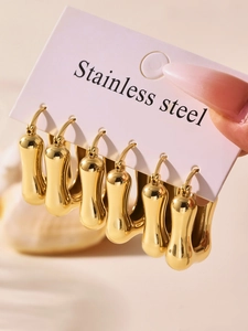 Close-up of three pairs of high-polished gold U-shaped earrings on a white card