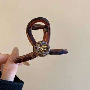 Detail view of tortoiseshell hair claw clip with leopard pattern and gold metal logo