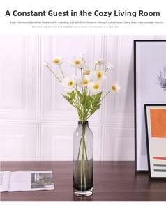 Close-up of white silk poppy flowers in a tall grey transparent glass vase for home decor