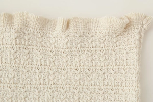Gros plan sur la texture du tricot crème montrant les détails du tissage épais