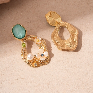 Detailed view of vintage gold flower earrings with green gems, pearls and rhinestones