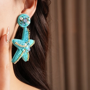 Detail shot of a model wearing the blue beaded starfish earring with crystal accents