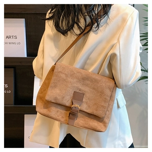 Khaki faux suede crossbody bag worn over a beige suit in a minimalist lifestyle setting