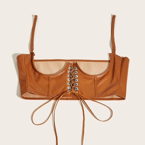 Détail du haut corset en similicuir marron avec laçage croisé et œillets métalliques