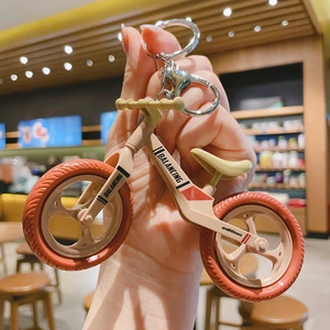 Detail of balance bike keychain in cream and orange with metal lobster clasp