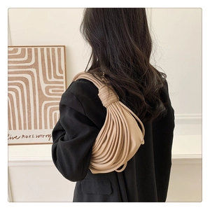 Detail of light beige shoulder bag featuring a unique knotted rope design and wave texture