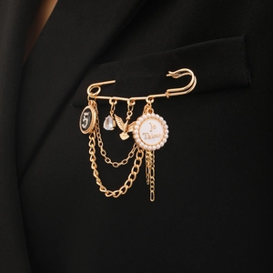 Detailansicht der goldenen Sicherheitsnadel-Brosche mit Quaste und Je Taime Perle am Blazer