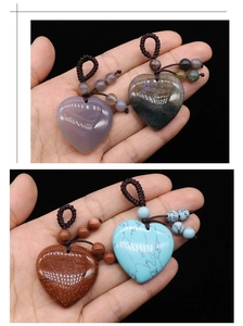 Close-up of hand holding four woven heart pendants made of natural agate gemstone