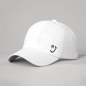 Detail shot of a white cotton baseball cap showing side smiley face print and texture