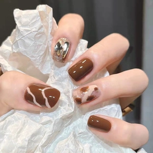Detailed view of brown cow print press-on nails with luxury rhinestone bow accent