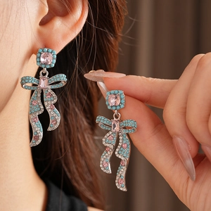 Gros plan détaillé des boucles d'oreilles nœud avec pierres roses et turquoise sur argent