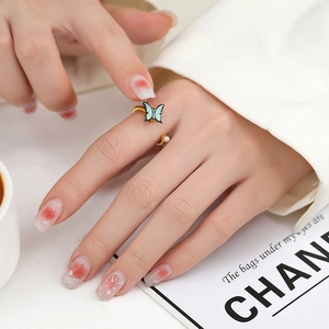 Detailed close-up of a rotating daisy ring with light blue butterfly and small white pearl