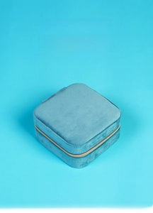 Detailed view of portable blue velvet jewelry box with golden zipper closure and soft lining
