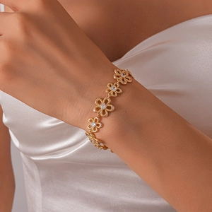 Detailed view of hollow flower bracelet with zircons on a model wearing white silk