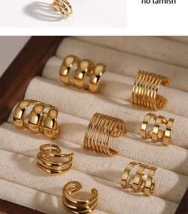 Detailed macro view of multiple gold geometric stripe ear cuffs on beige velvet display