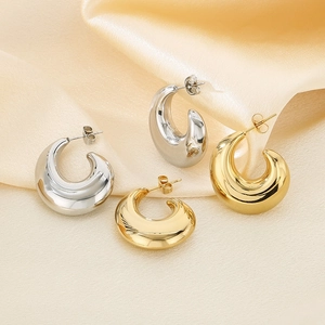 Boucles d'oreilles goutte polies en or et argent sur fond élégant en soie jaune