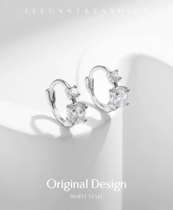 Détail macro de boucles d'oreilles en argent 925 avec zircons sur socle blanc