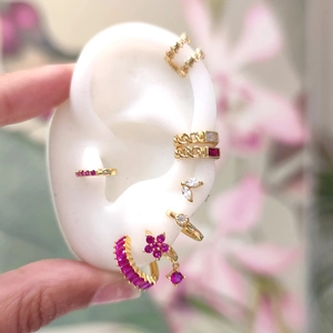 Detail view of gold earrings with pink and clear zircons on a realistic ear model