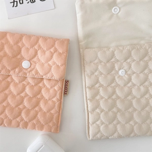 Close-up of quilted heart pattern pouches with snap button and brand label detail