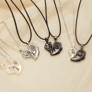 Detail of magnetic couple necklaces featuring heart wing pendants and 100 languages projection