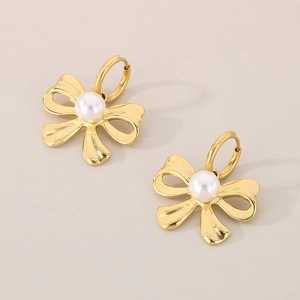 Detailed view of vintage golden bow earrings with elegant white pearl center accents