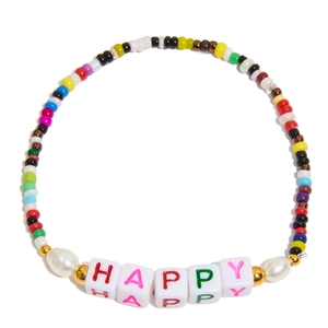 Macro detail of colorful beaded HAPPY bracelet with white pearls and gold accents