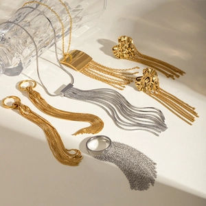 Elegant gold and silver tassel jewelry set including necklace, earrings and ring on beige background