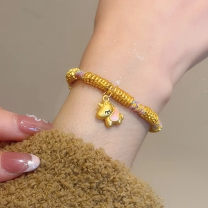 Detail of a braided gold bracelet with unicorn pendant and pink enamel craft details