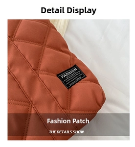 Detail of diamond quilted stitching and brand label on a brick red nylon tote bag