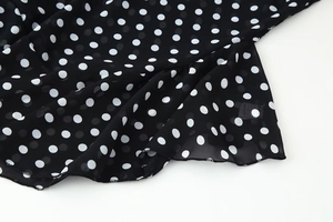 Detailed view of black and white polka dot chiffon fabric with ruffled edge design