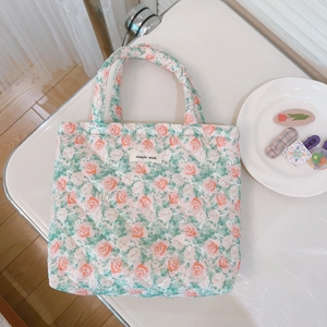 Detailed macro view of quilted floral tote bag with green rose pattern and label