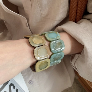 Detail of amber and green resin square link bracelets with marble texture on model wrist