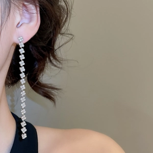Detailed close-up of silver square tassel earrings with sparkling rhinestones on model