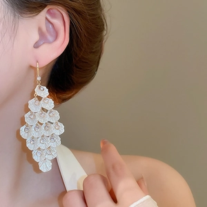 Detail of white flower petal tassel earrings with zircon studs on a female model