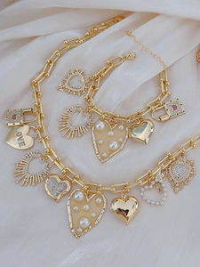 Detail von goldenem Halsketten- und Armbandset mit Herzanhängern und Perlenverzierung