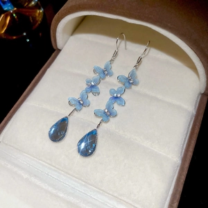 Detail of blue layered butterfly earrings with a teardrop crystal pendant in a jewelry box