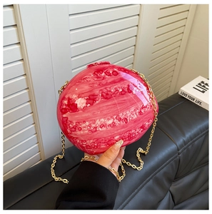 Detailed shot of pink marble acrylic spherical clutch bag with golden chain strap