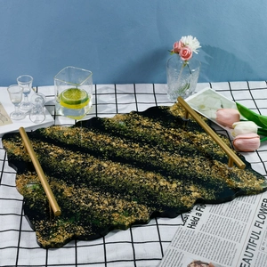 Close-up of irregular resin tray with green marbling, gold foil flakes, and metal handles