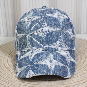 Detail of light blue denim baseball cap with silver sequins and white star patterns