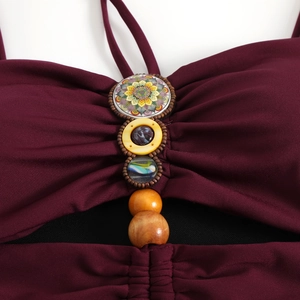 Detail of burgundy swimsuit featuring bohemian beads and mandala pattern ornament