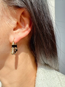 Macro side view of geometric trapezoid earrings with black enamel and gold plating