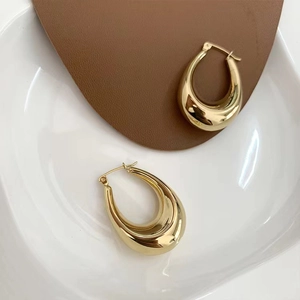 Detailed view of hollow teardrop earrings with mirror-polished 18K gold finish on a tray