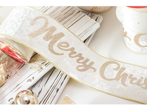 Close-up of premium champagne velvet Christmas ribbon with gold Merry Christmas lettering