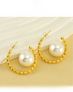 Detailed view of large white pearl set in gold-plated titanium steel hoop earrings