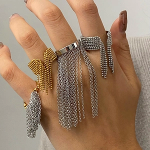 Detailed view of gold and silver tassel rings with bead bow design on a person's hand
