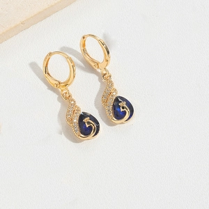 Detail view of gold peacock drop earrings with blue teardrop stones and small diamonds