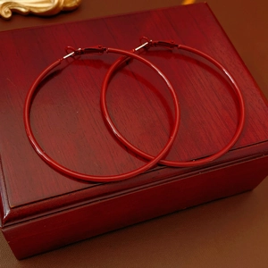 Close-up of vintage glossy red hoop earrings displayed on a dark premium wood box
