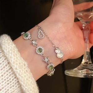 Close-up of zircon flower bracelet and white gourd charm on a wrist with a glass